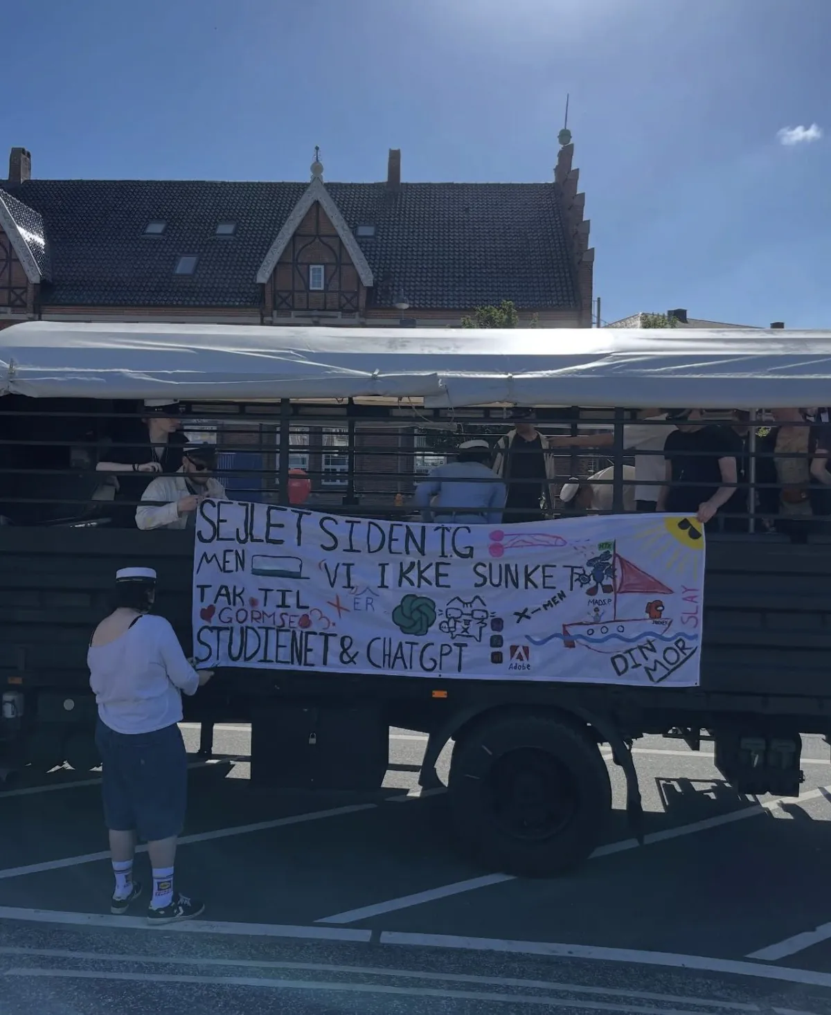 Studenter hænger et hjemmelavet banner op på siden af en studentervogn i Silkeborg